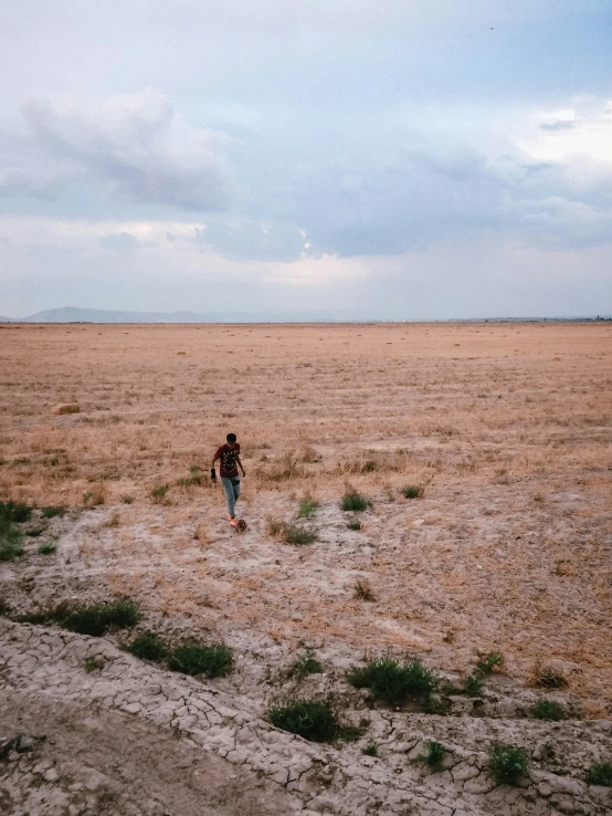 a lone man standing in a desert field