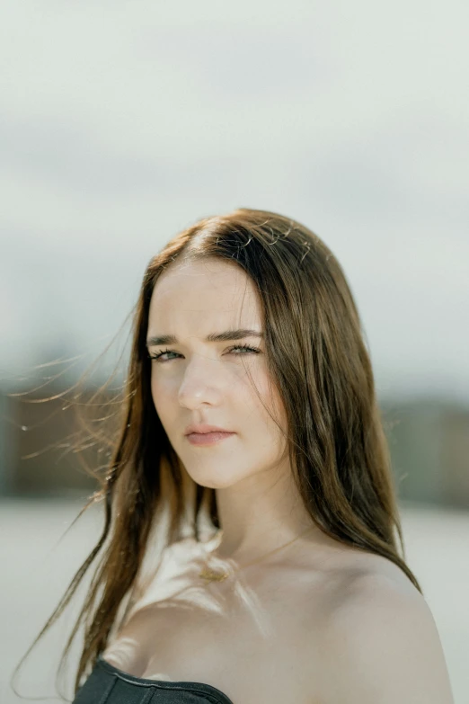 a woman with long hair is wearing black shirt and a gray background