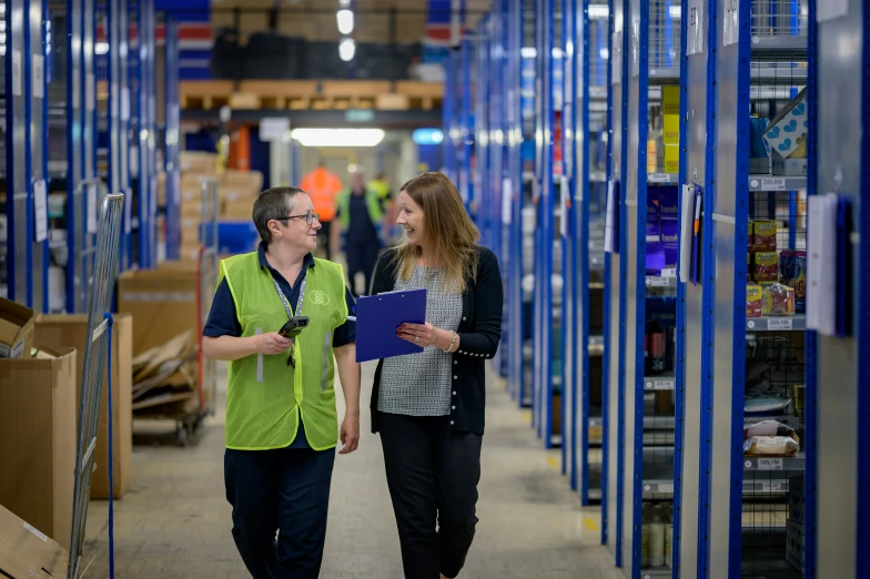 two people talking inside a blue metal filled warehouse