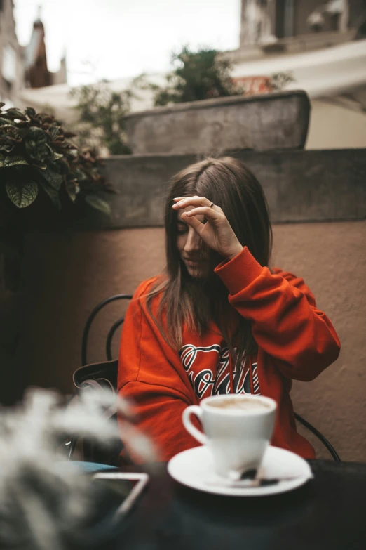 a woman sitting down at a table holding her hands over her eyes