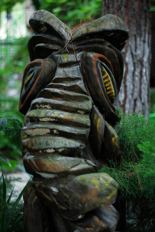 a large wooden carved insect standing next to a tree