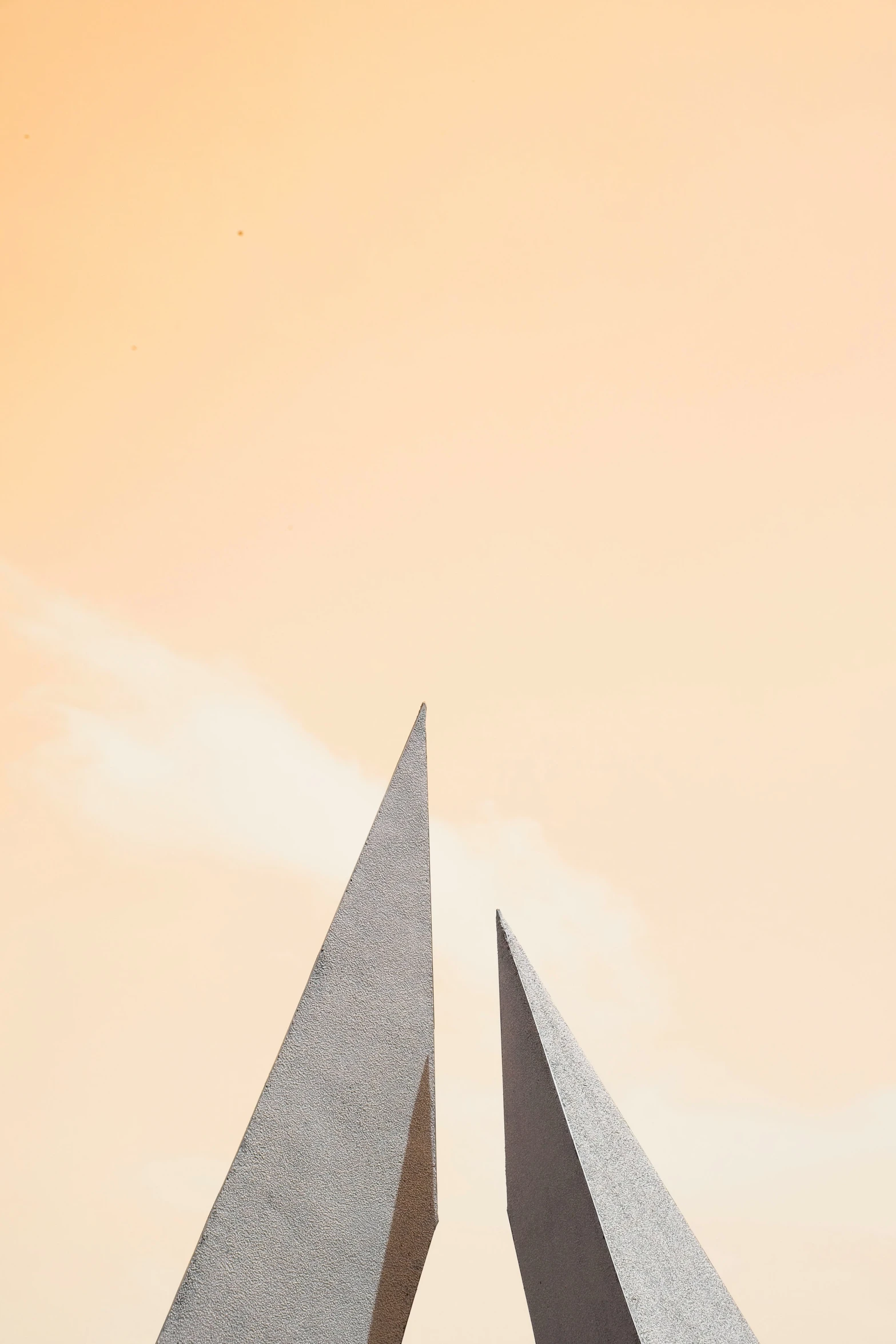 two sculptures with long slender stands against a bright sky