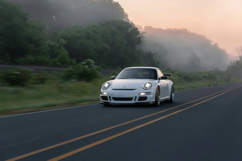 a white sports car on a highway near trees