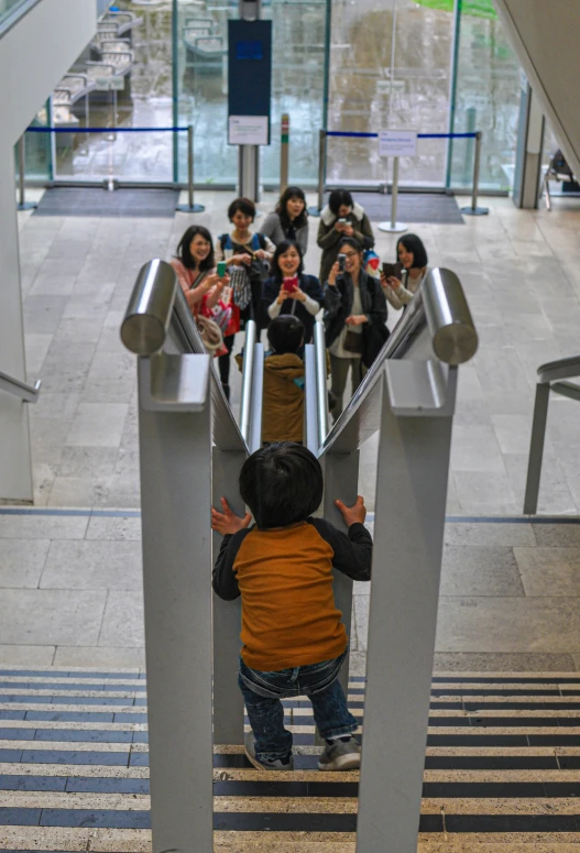 a young child rides down an escalator while others watch