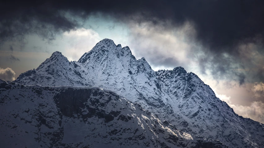 snow - covered mountains are against a cloudy sky