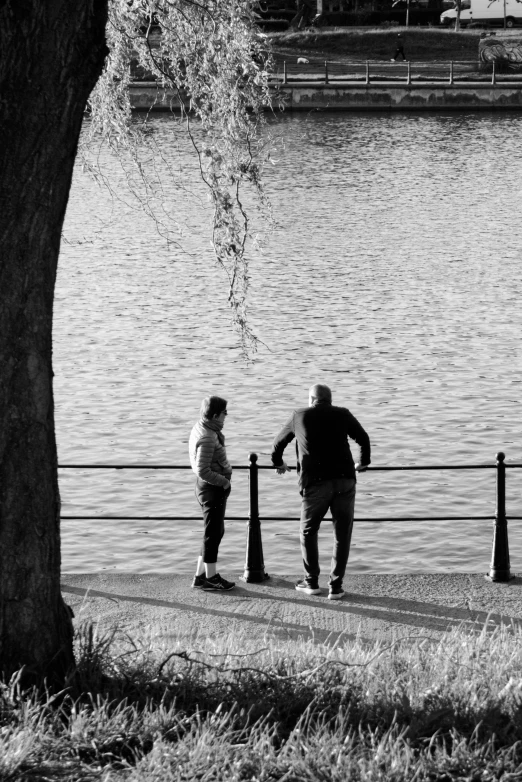 two men walking past a large body of water