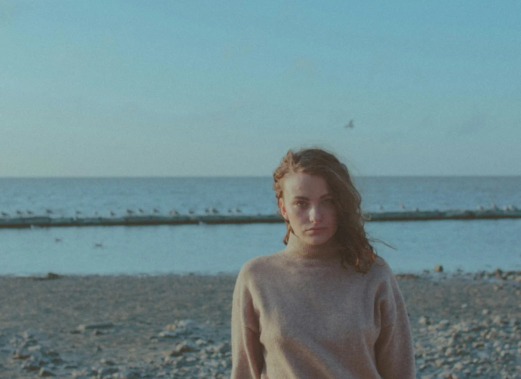 a girl in light clothing stands on the beach