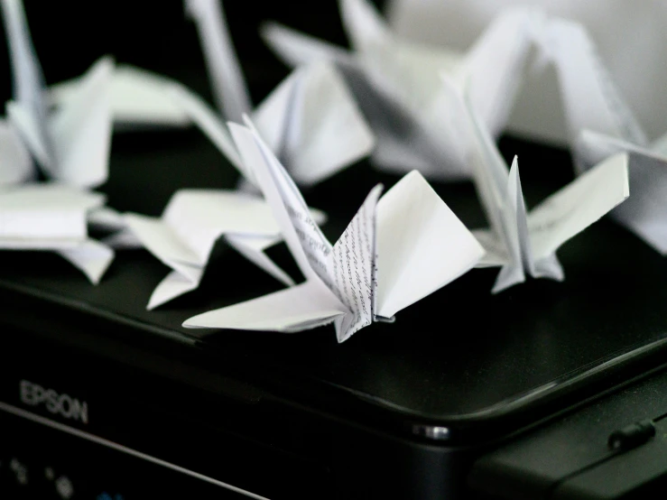 origami cranes sit on top of an open laptop