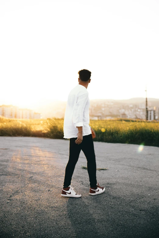 a man wearing a hat and white shirt walks down a road