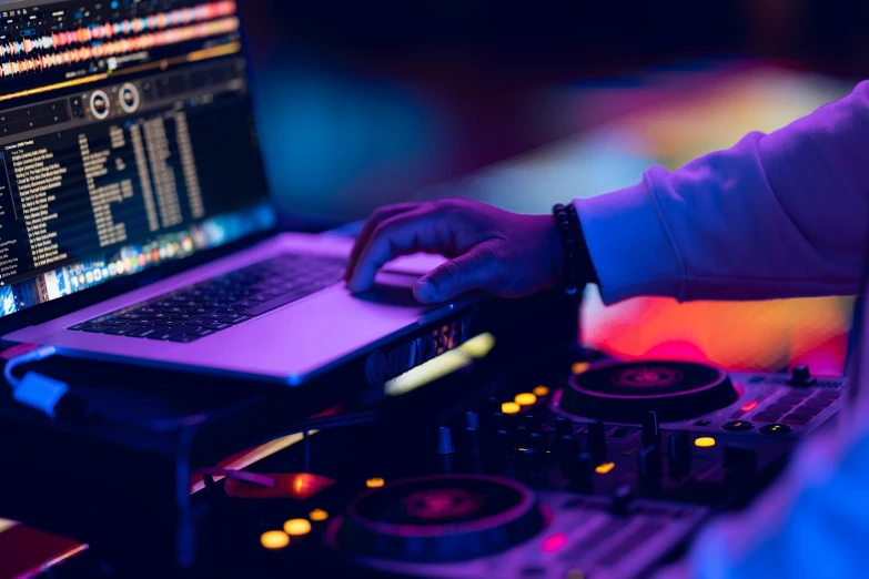 a person is using a laptop computer next to the djs controllers