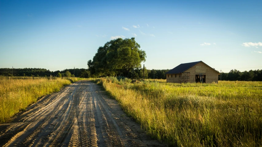 a dirt road runs alongside an old building