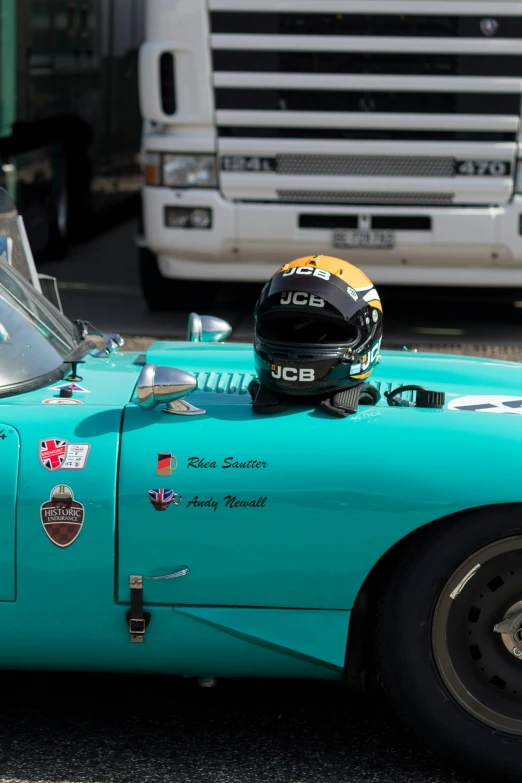 a man sitting in a green vintage car next to other vehicles