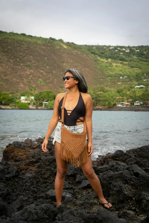 a beautiful woman in a bikini top standing on rocks