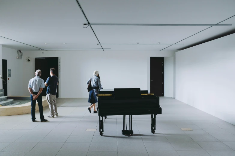 two people in a large room with a black piano