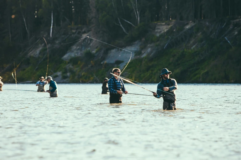 several men standing in water holding on to fishing rods