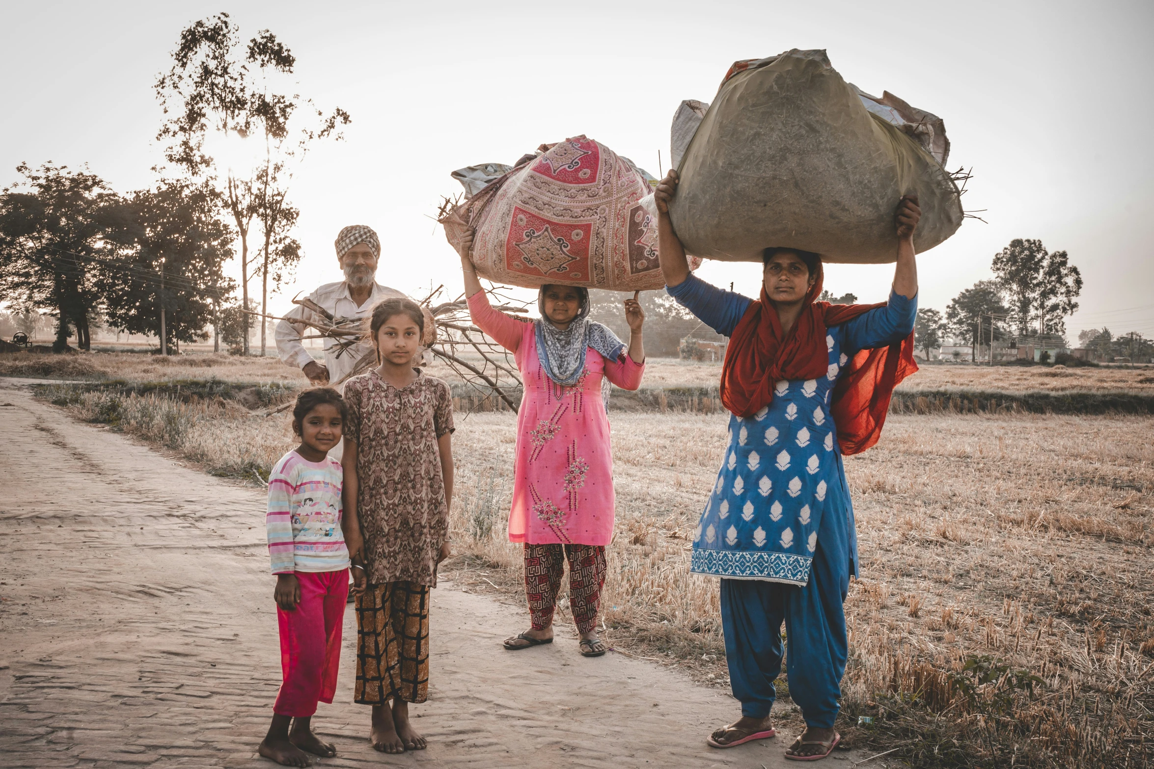 three girls in colorful clothing carrying bags and baskets