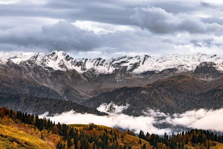 a snowy mountain and some clouds with trees