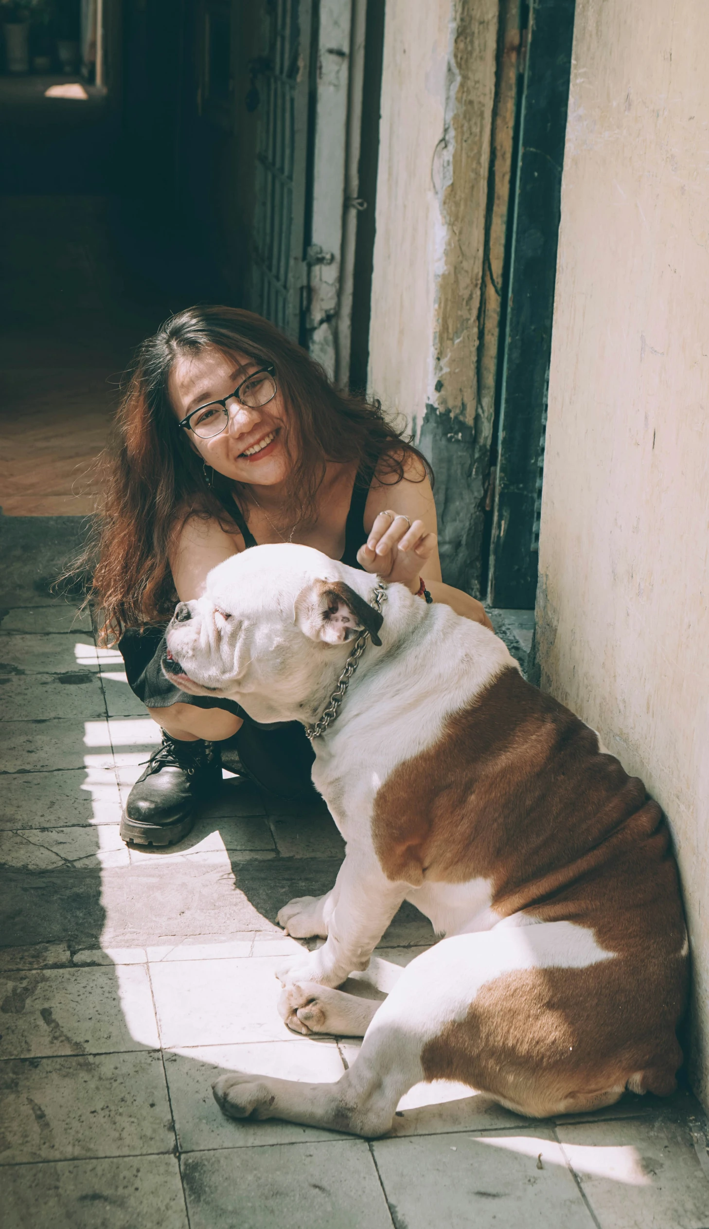 a smiling woman pets a brown and white dog