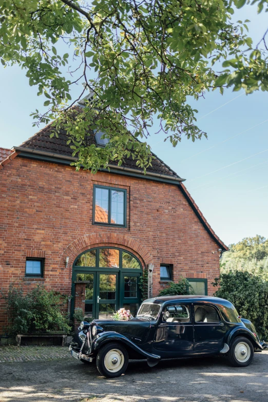 an antique car is parked in front of a house