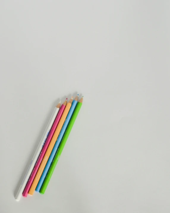 six colored pencils with white tops and green tipped ones