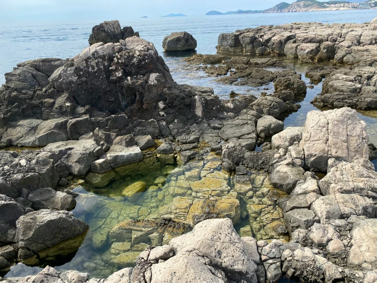 an ocean view with small rocks on the shore