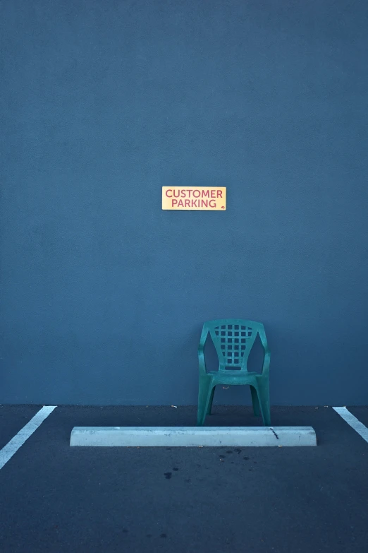 a bench on a empty parking lot near a blue wall