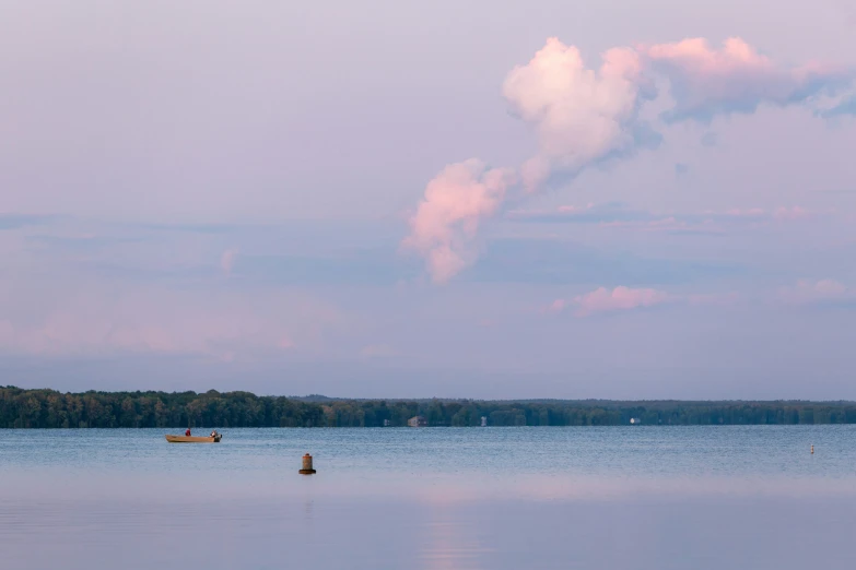 two small boats floating on the lake at sunset