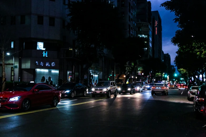 several cars are driving down the road at night