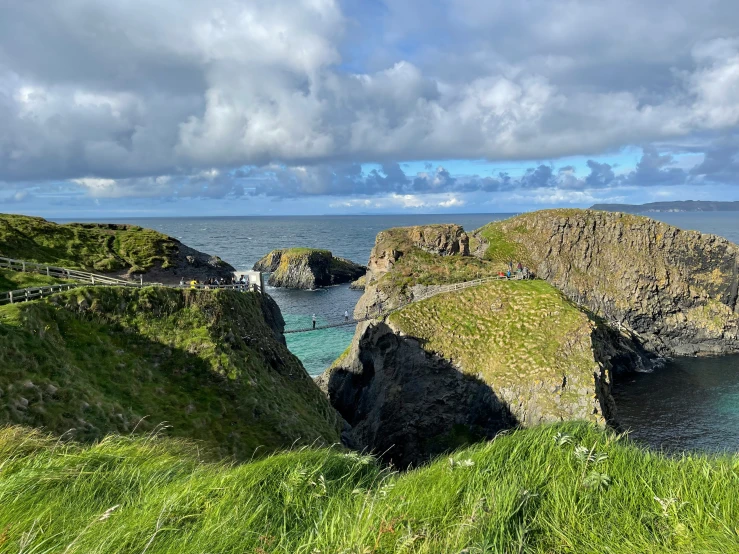 people walking across a rope bridge over water