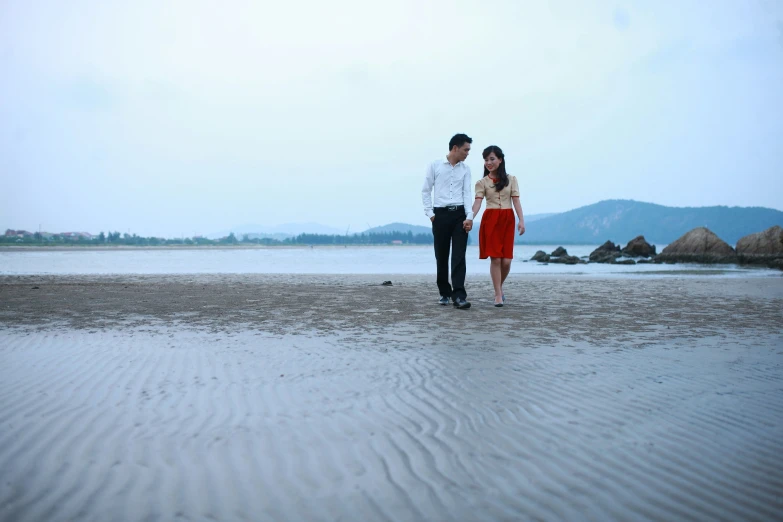 a woman standing next to a man on a beach