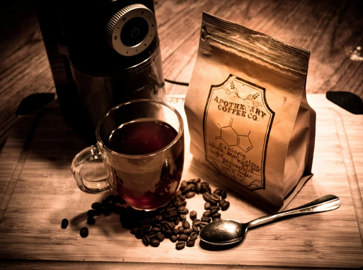 a coffee bag sitting on top of a wooden table next to a cup of coffee