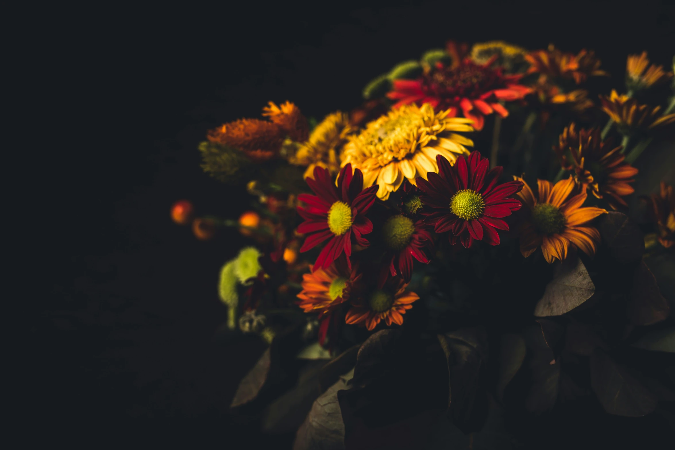 a vase filled with lots of red yellow and green flowers