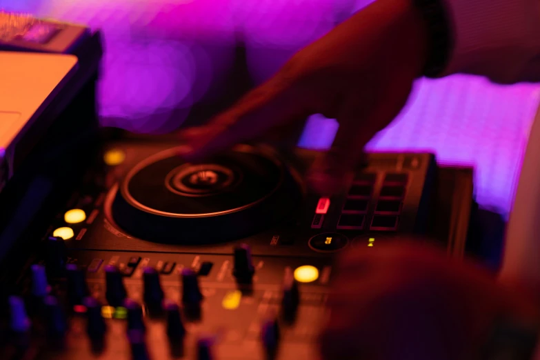 a dj mixing at an event, with purple light