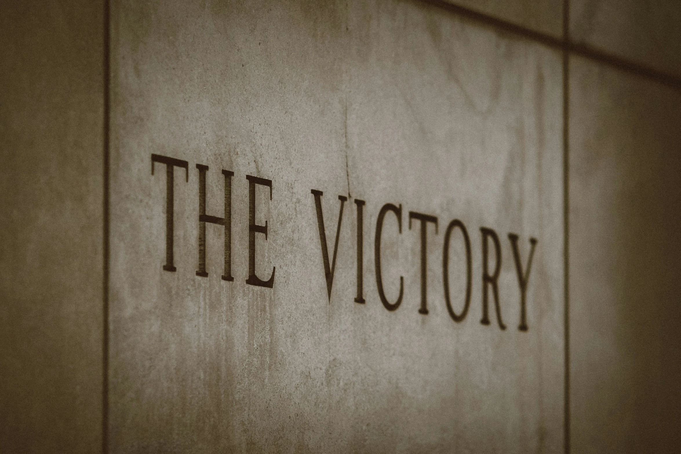 close up view of the word the victory on a concrete wall