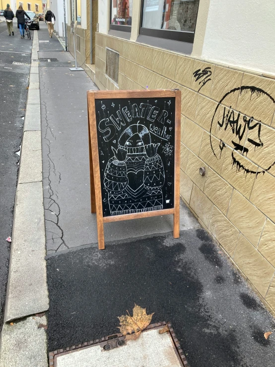 a chalk board in front of a building with graffiti on it