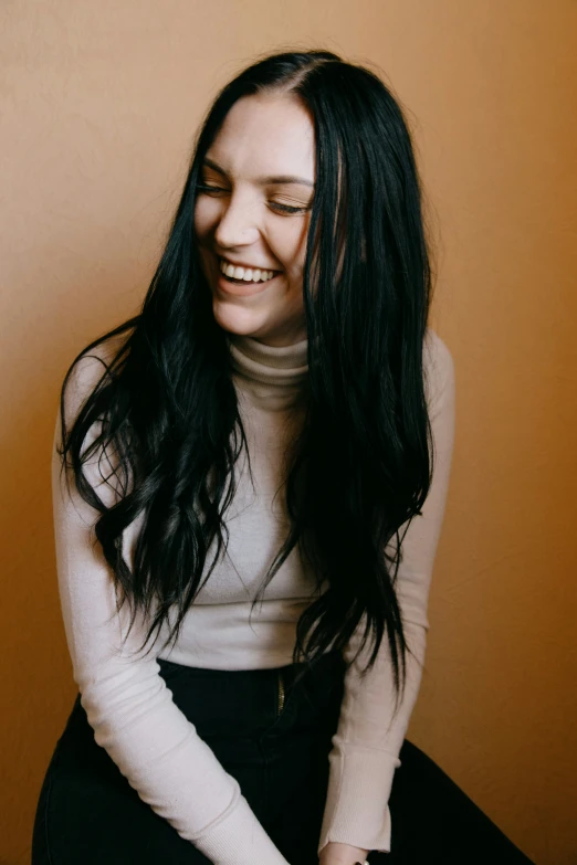 a girl is sitting smiling with her long hair blowing back