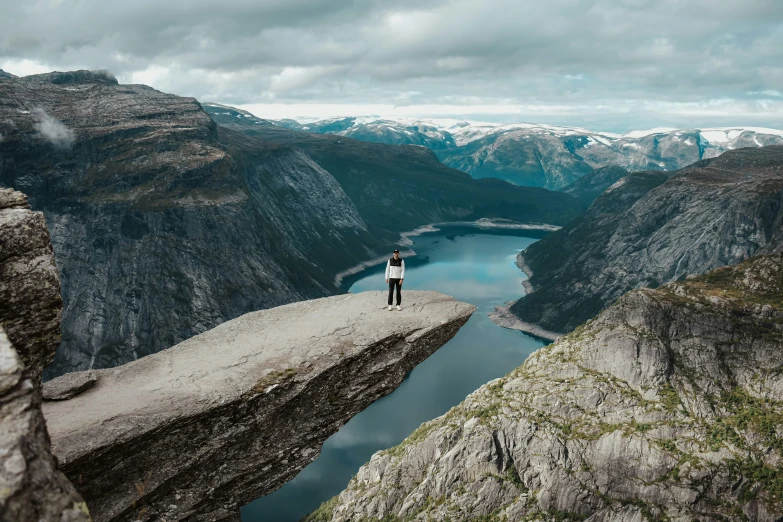 a person standing on top of a cliff next to a body of water