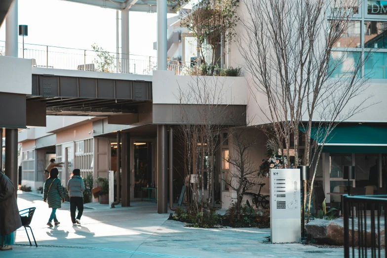 some people are walking past two buildings and one is in the shade