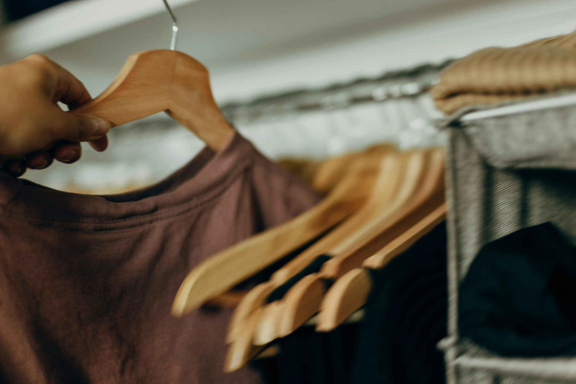 a person holding a t shirt with clothes on hangers