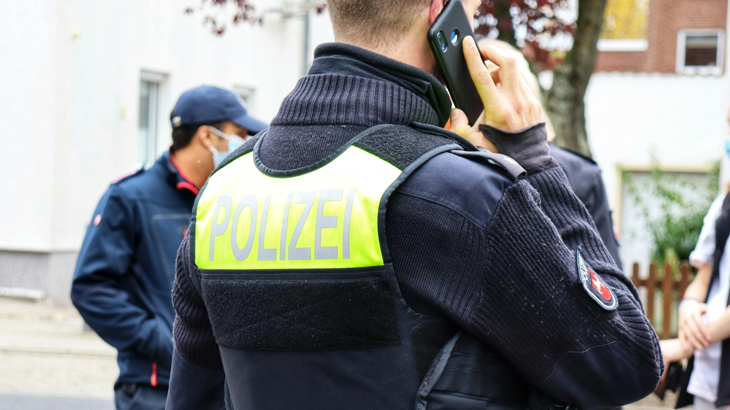 two men talking on cell phones standing in a street