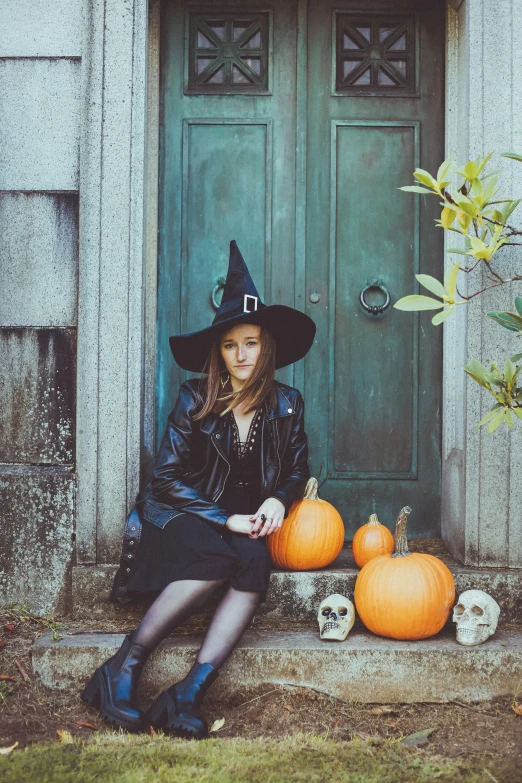 a beautiful woman in a witches outfit sitting on the steps