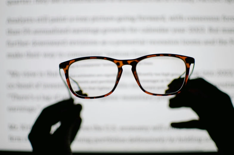 someone holding up a pair of glasses to show it