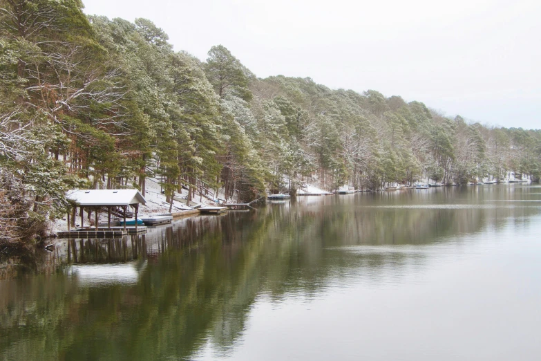 the snow on the trees is covering the calm water