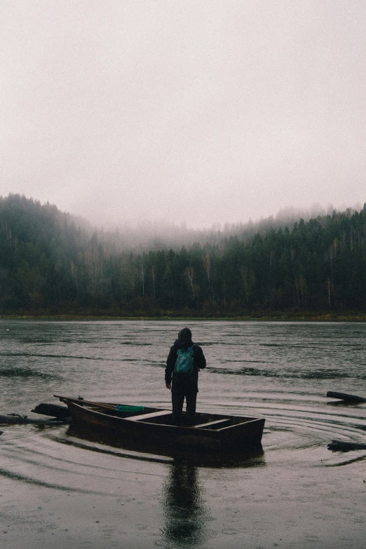 a man standing in a small boat on a lake