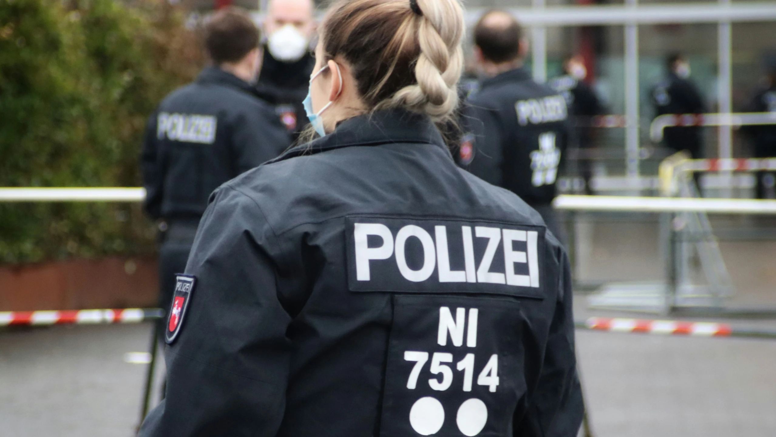 a police officer standing in front of a building wearing medical mask