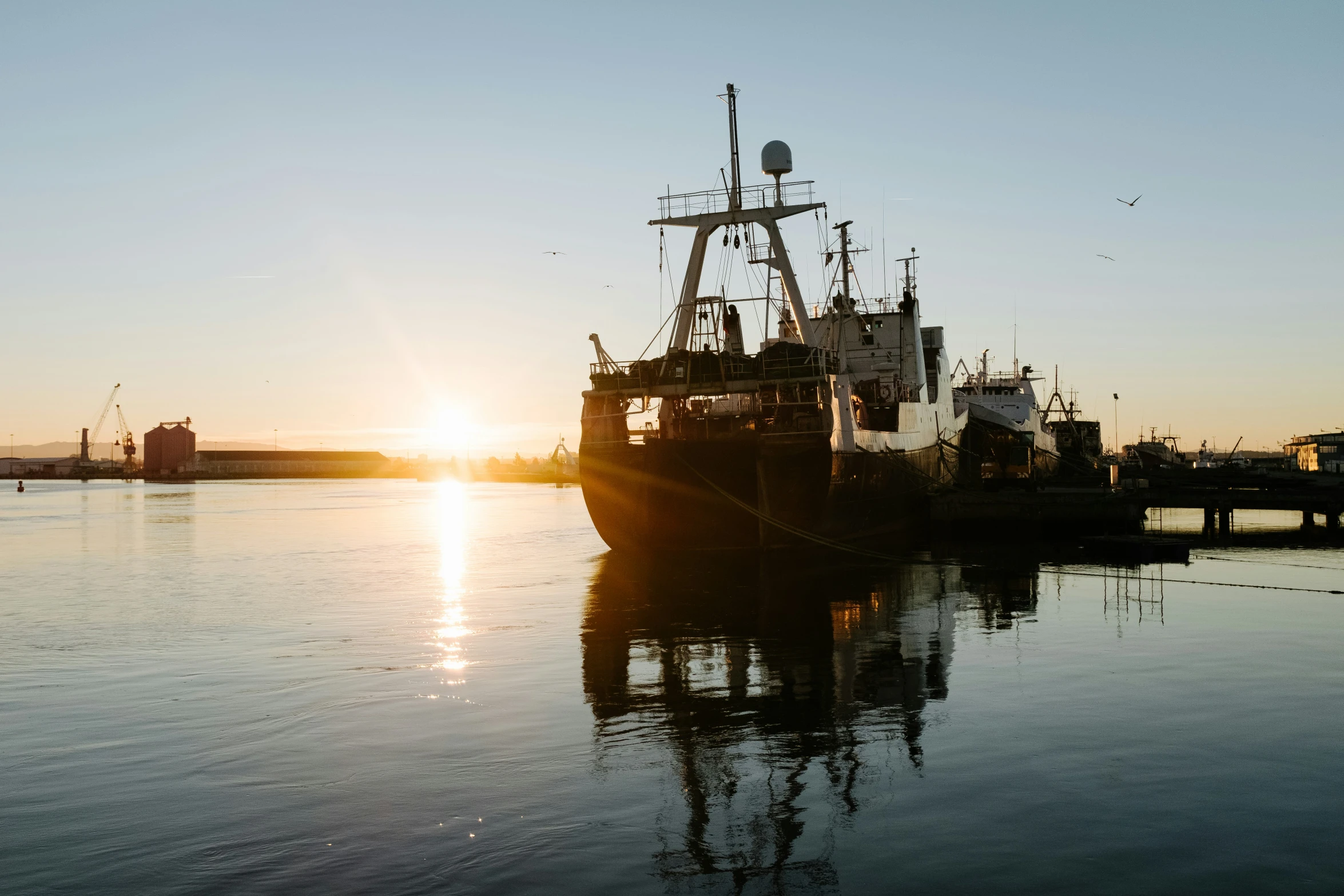 the sun is setting over the water in this harbor