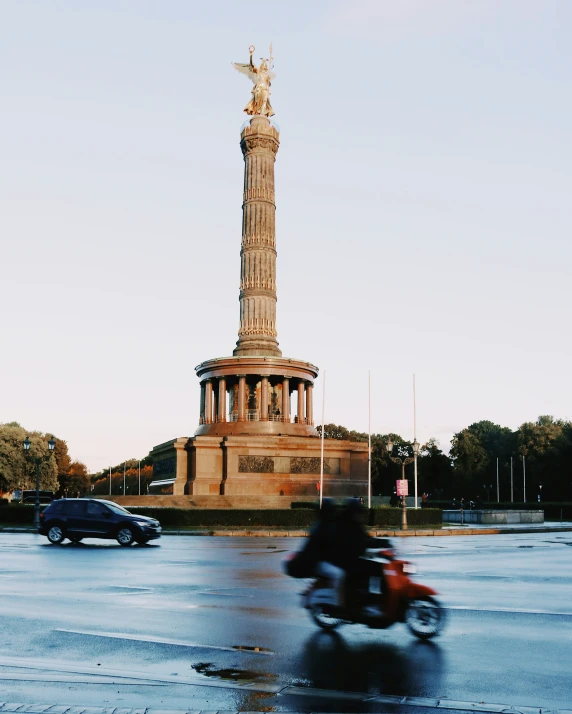 a person riding a bike in front of a statue