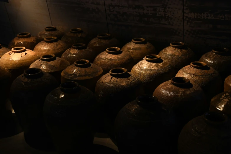 a line of large vases sitting in front of a wall