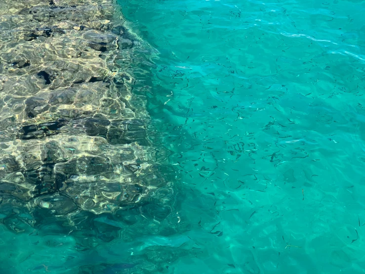 blue water and the bottom of a ship with rocks sticking out