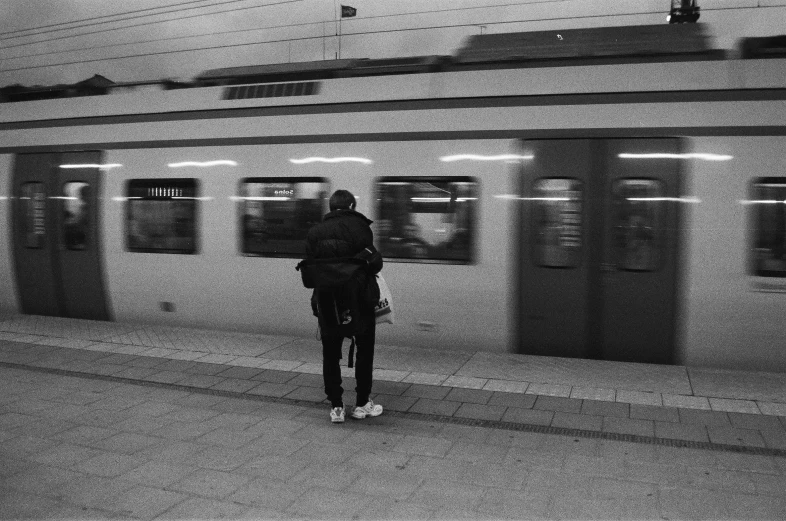 a person standing on a subway platform with a train in the background